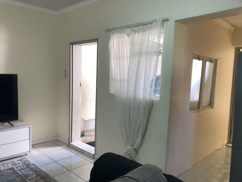 A living area featuring tiled flooring and multiple internal access points, showing signs of wear and dated finishes.