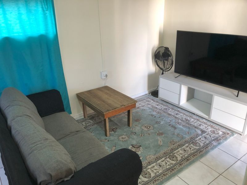 A simple living room area featuring tiled flooring and neutral wall finishes, providing a functional space for relaxation.