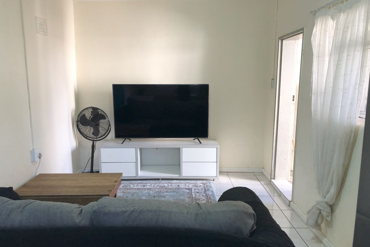 A functional living room space featuring tiled flooring and neutral wall finishes, providing a simple and practical area for relaxation.