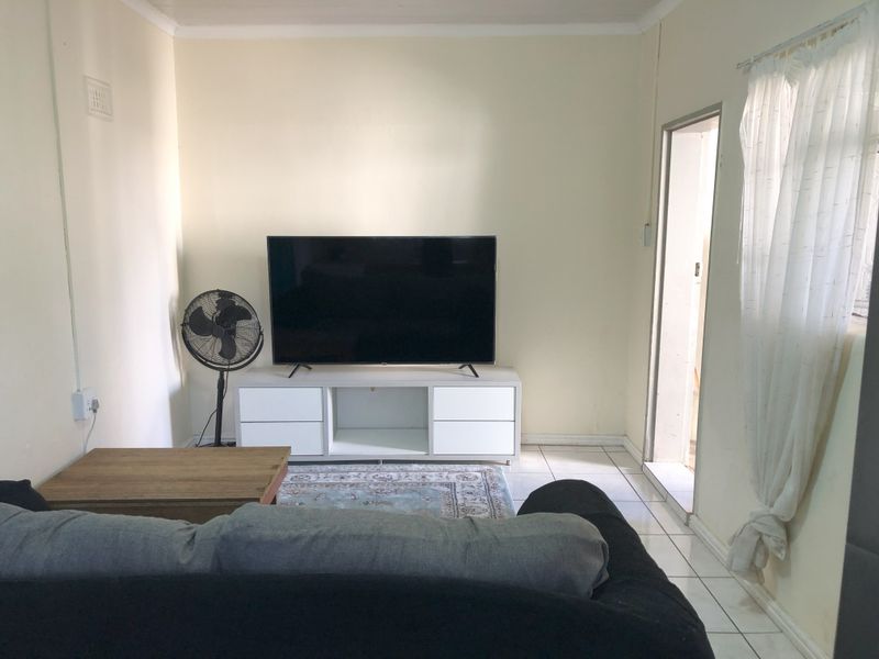 A functional living room space featuring tiled flooring and neutral wall finishes, providing a simple and practical area for relaxation.