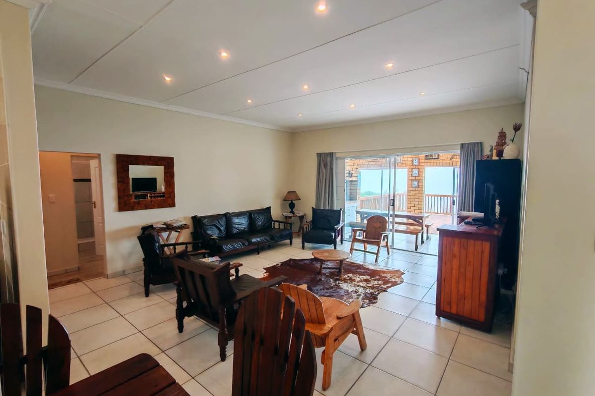 Spacious living room featuring tiled flooring, recessed downlighting, and large sliding glass doors providing access to an outdoor patio area.