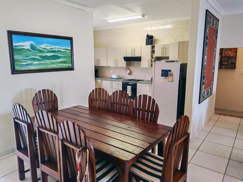 Open plan dining area adjacent to a functional kitchen featuring built-in cabinetry, tiled backsplash, and integrated cooking appliances.