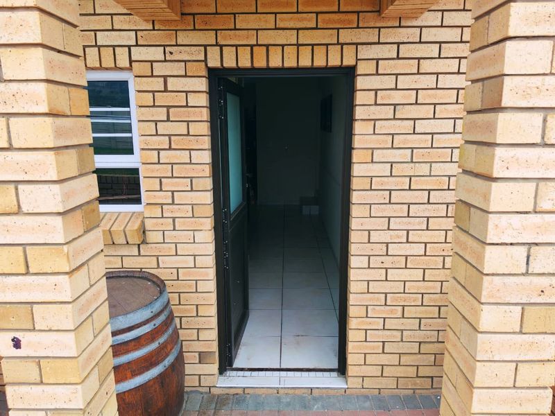 A clear view of the property entrance featuring a face brick facade, tiled flooring, and a secure entrance door.