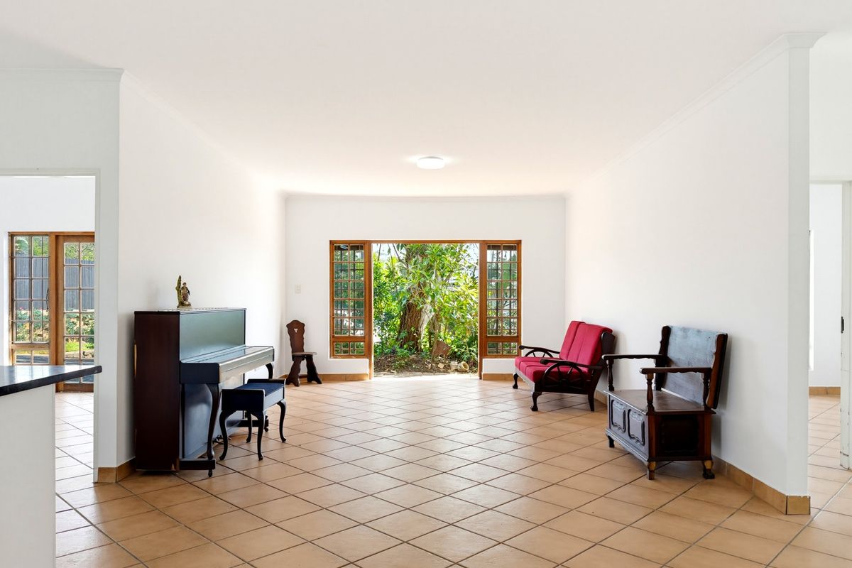 Spacious living area featuring neutral walls, tiled flooring, and large wooden-framed glass doors providing direct access to the garden.