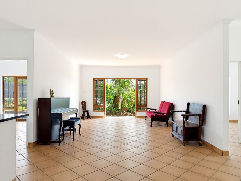 Spacious living area featuring neutral walls, tiled flooring, and large wooden-framed glass doors providing direct access to the garden.