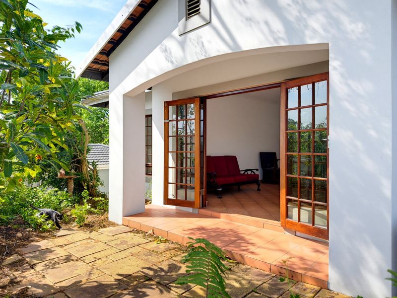 A covered patio area featuring terracotta tiling and timber-framed French doors providing seamless access to the interior living space.