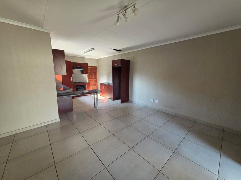 Open-plan living and kitchen area featuring tiled flooring, built-in cabinetry, and a breakfast bar, requiring minor ceiling and wall repairs.