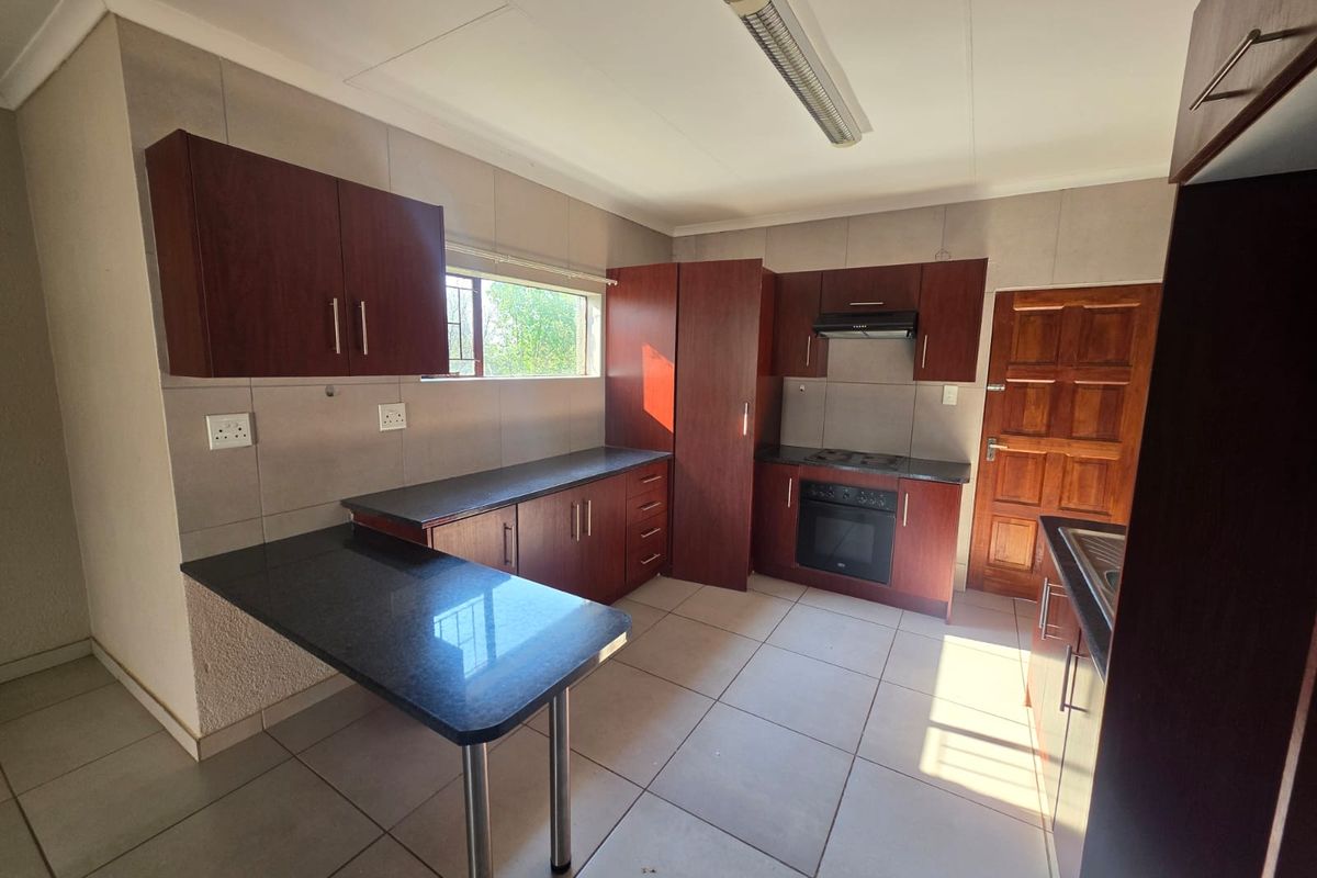 A functional kitchen featuring dark wood cabinetry, granite countertops, built-in oven and hob, and tiled flooring, offering a clean and practical workspace.