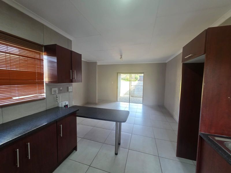 An open-plan kitchen and living area featuring dark wood cabinetry, tiled flooring, and a sliding door providing access to the exterior.