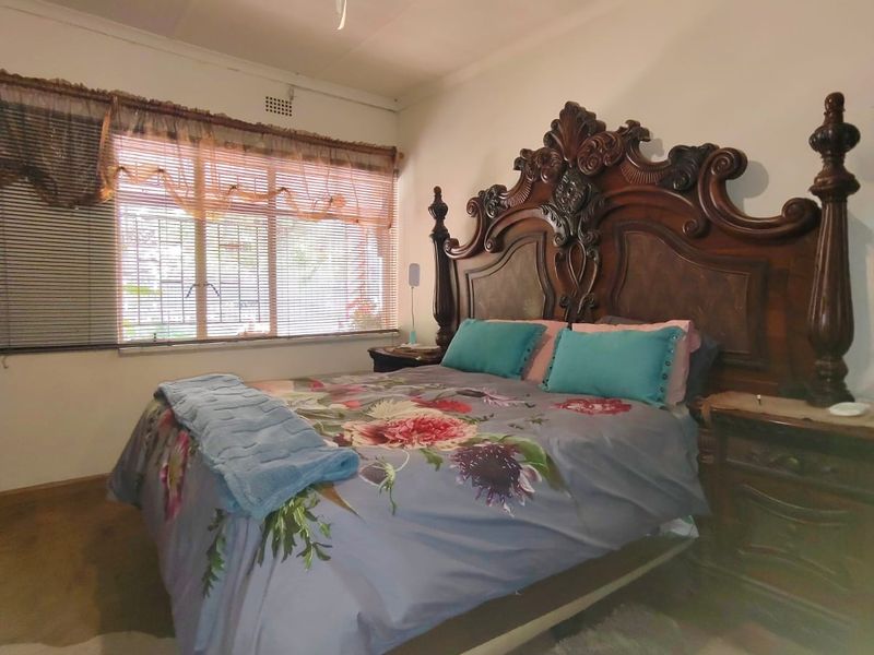 A standard bedroom featuring a ceiling fan and a window with blinds, providing a functional space with neutral wall finishes.