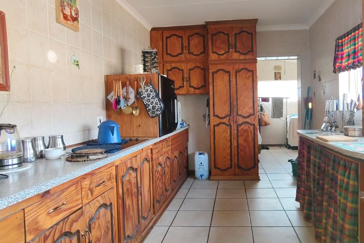 A functional kitchen featuring traditional wooden cabinetry, tiled flooring, and ample counter space, offering potential for a modern renovation.
