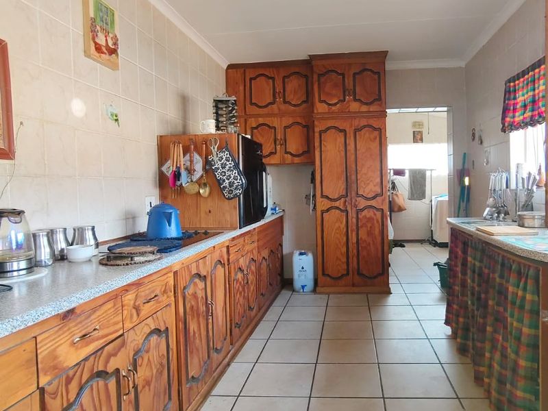 A functional kitchen featuring traditional wooden cabinetry, tiled flooring, and ample counter space, offering potential for a modern renovation.