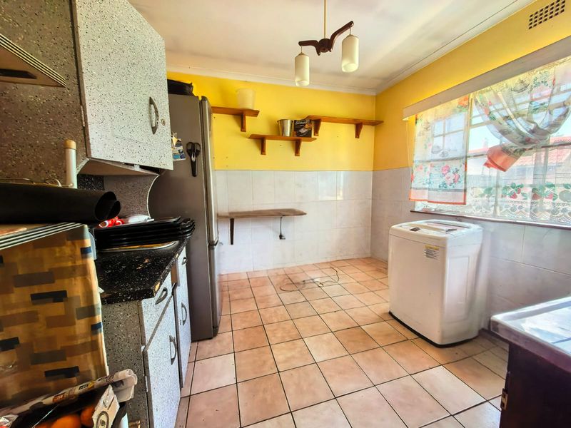 A functional kitchen featuring tiled flooring, wall tiling, and built-in cabinetry, offering a dated aesthetic with potential for modernization.