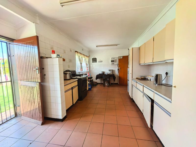 A functional kitchen featuring tiled flooring, ample built-in cabinetry, laminate countertops, and a stable door providing direct access to the exterior.