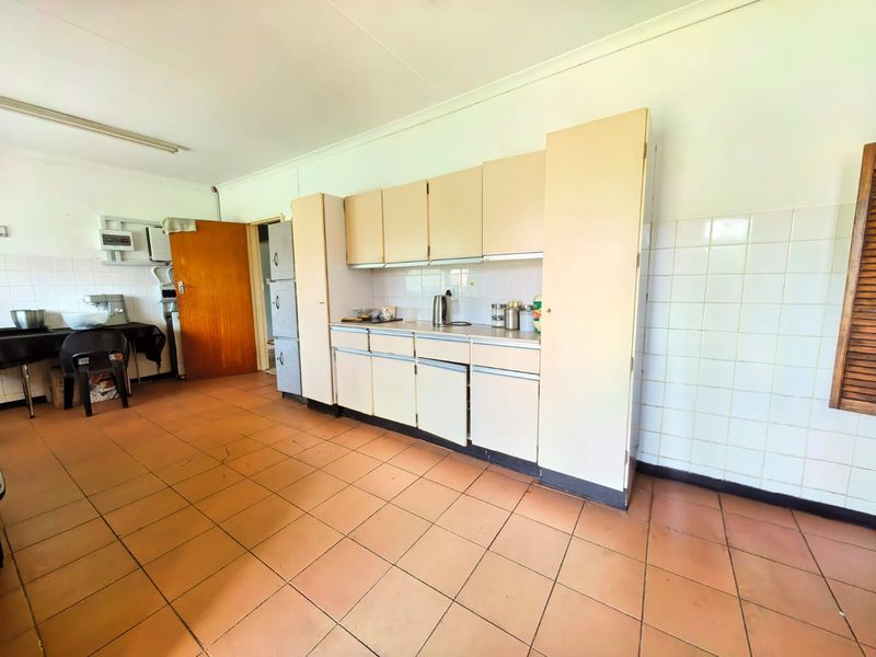 A dated kitchen featuring original built-in cabinetry, tiled flooring, and a tiled splashback, offering significant potential for a modern renovation.