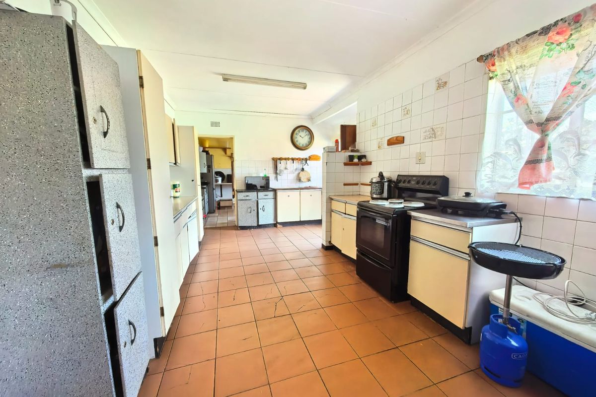 A spacious, dated kitchen featuring tiled flooring, extensive cabinetry, and a freestanding oven, offering significant potential for a modern renovation.