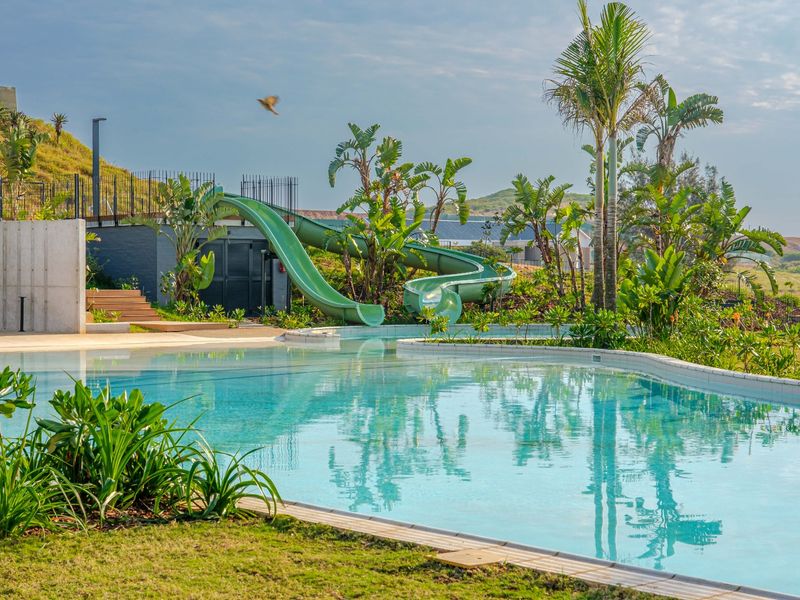 A well-maintained swimming pool area featuring a water slide, landscaped surroundings, and modern retaining walls, offering a high-quality recreational space.
