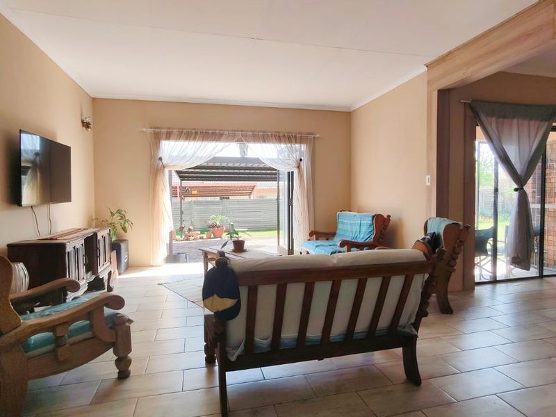 Spacious living room featuring neutral wall tones, tiled flooring, and large sliding glass doors providing direct access to the outdoor patio area.