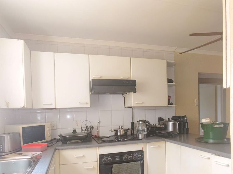 A functional kitchen featuring built-in cabinetry, a gas hob with extractor fan, built-in oven, and tiled backsplash, offering potential for modern updates.