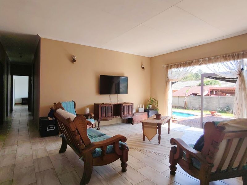 Spacious living room featuring tiled flooring and large sliding glass doors that provide direct access to the outdoor pool area.
