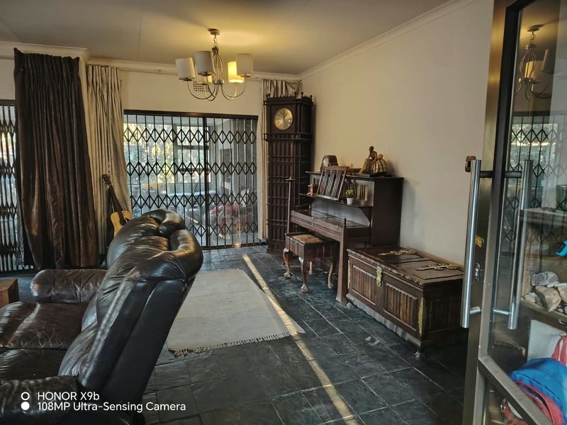 A living room featuring dark slate tile flooring, a chandelier, and a sliding glass door with a security gate leading to the exterior.