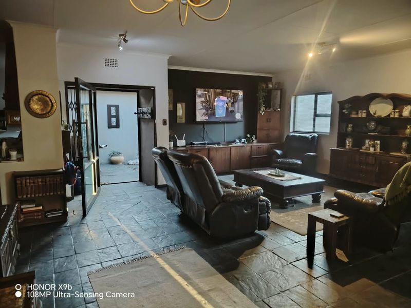 Spacious living room featuring dark slate tile flooring, built-in cabinetry, and direct access to an outdoor area through a security gate.