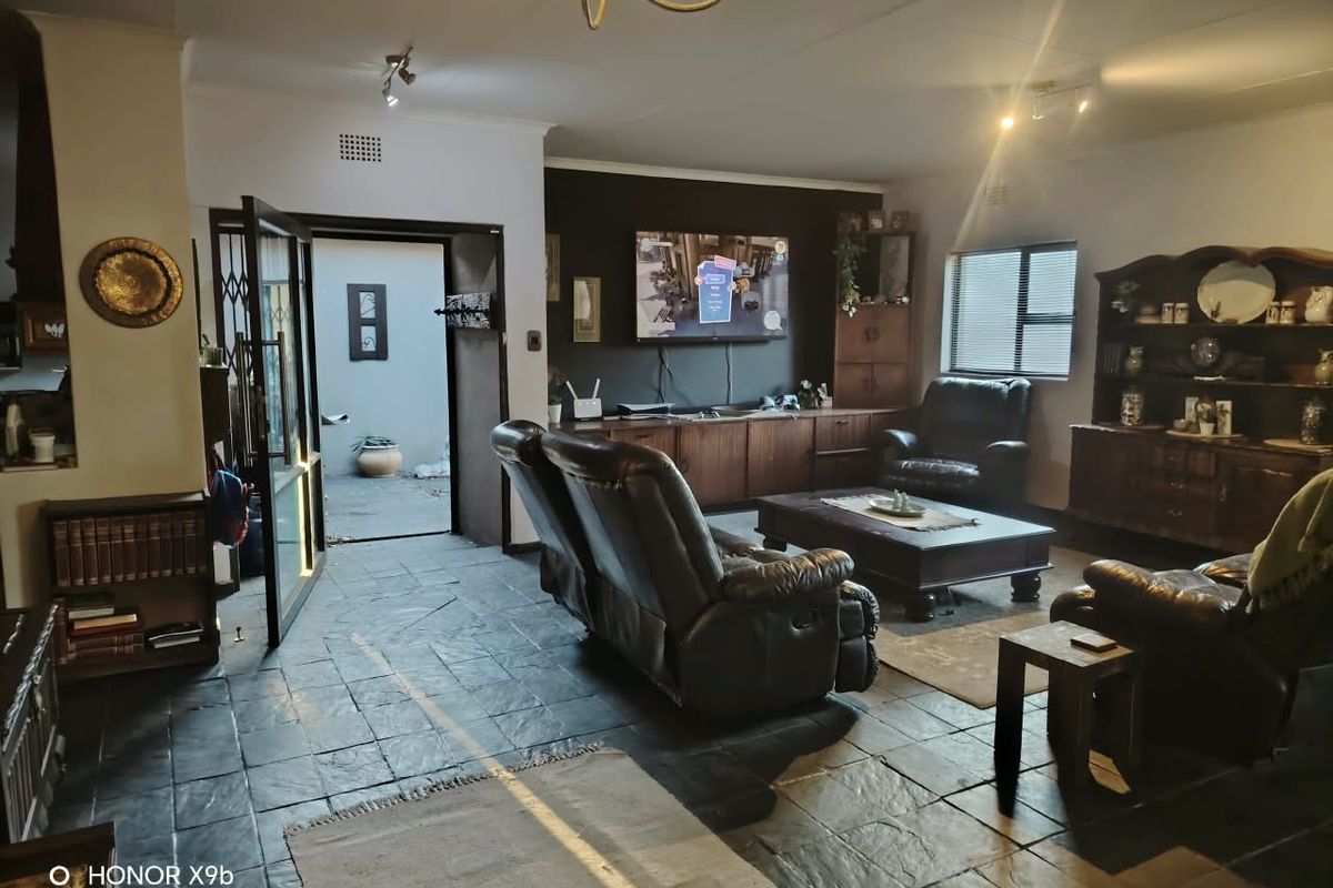 Spacious living room featuring dark slate tile flooring, built-in cabinetry, and direct access to an outdoor area through a security gate.