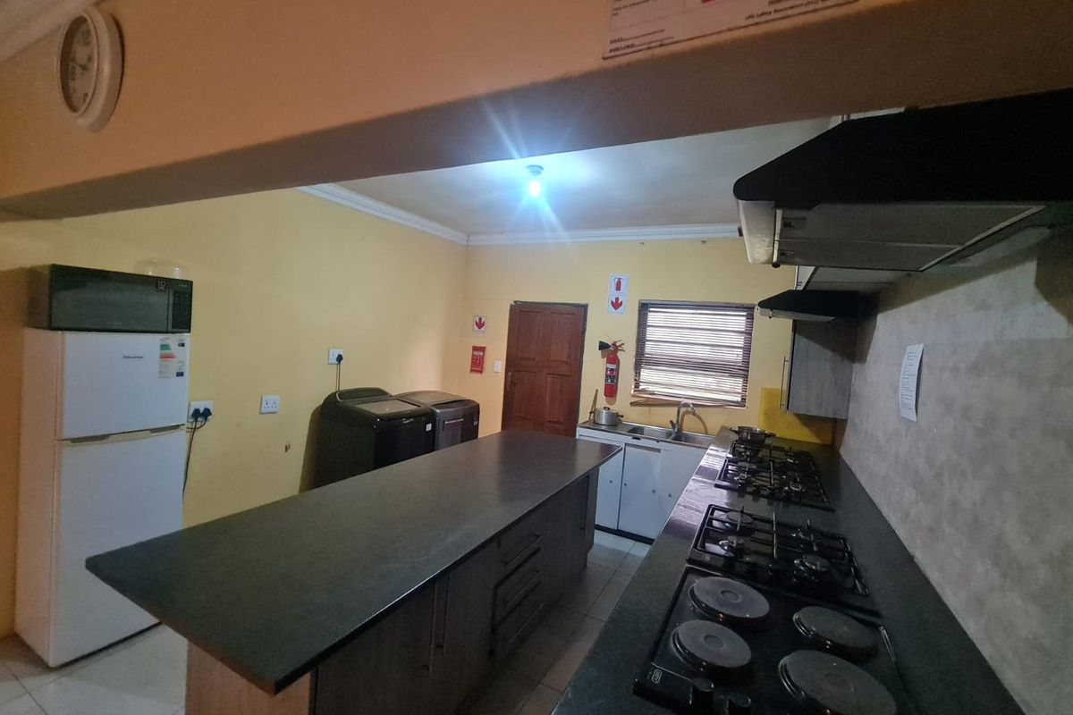 Functional kitchen featuring a large central island, dual hob setup, extractor fan, and ample cabinetry with tiled flooring.