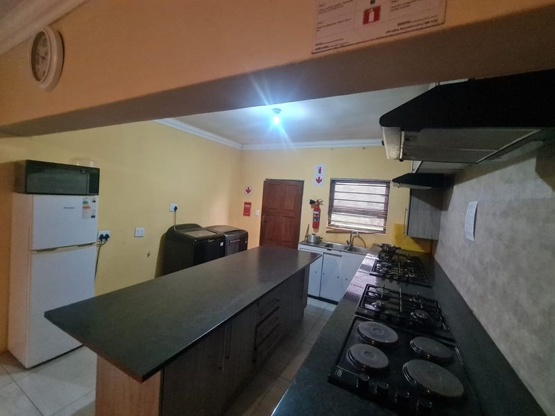 Functional kitchen featuring a large central island, dual hob setup, extractor fan, and ample cabinetry with tiled flooring.