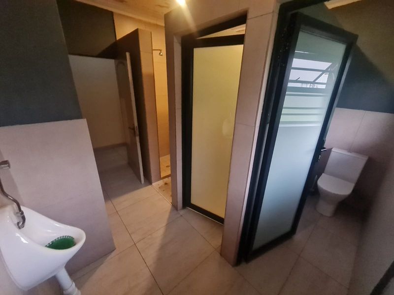 A functional bathroom featuring a urinal, a separate shower cubicle, and a toilet with tiled finishes throughout.