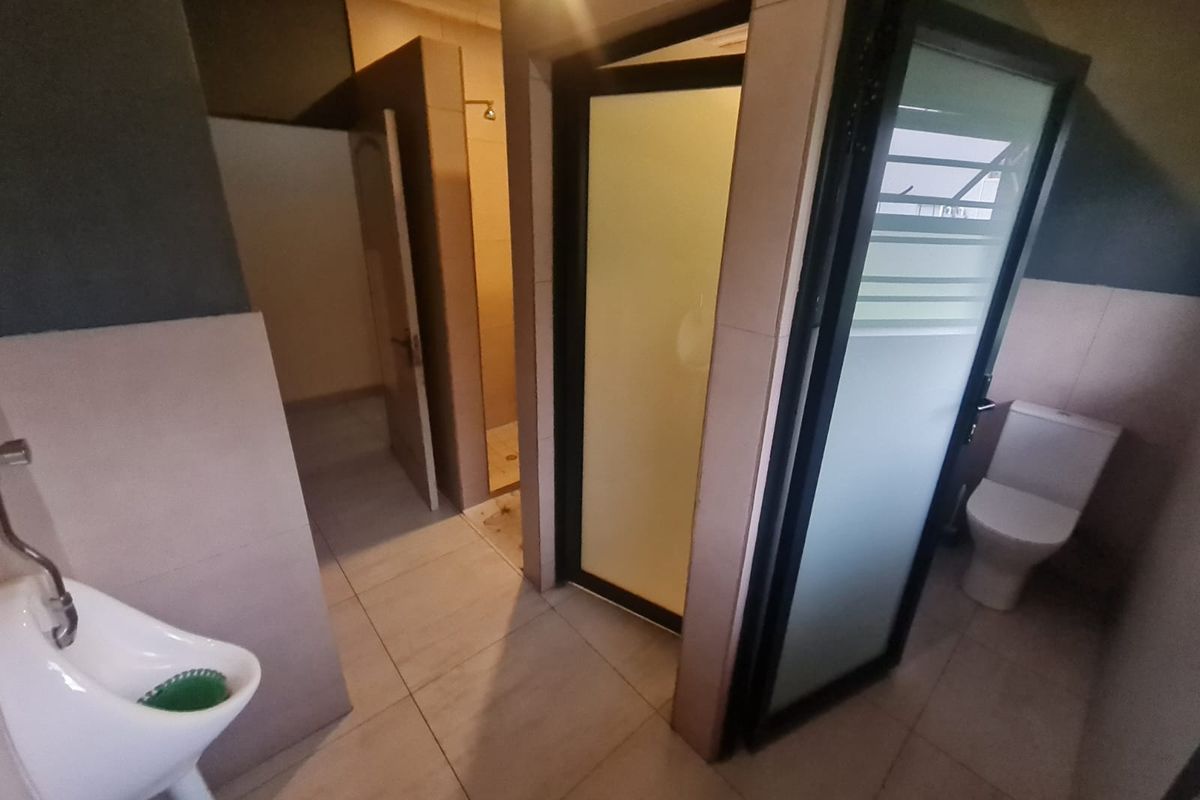 A functional bathroom featuring a urinal, a separate shower cubicle, and a toilet with tiled finishes throughout.