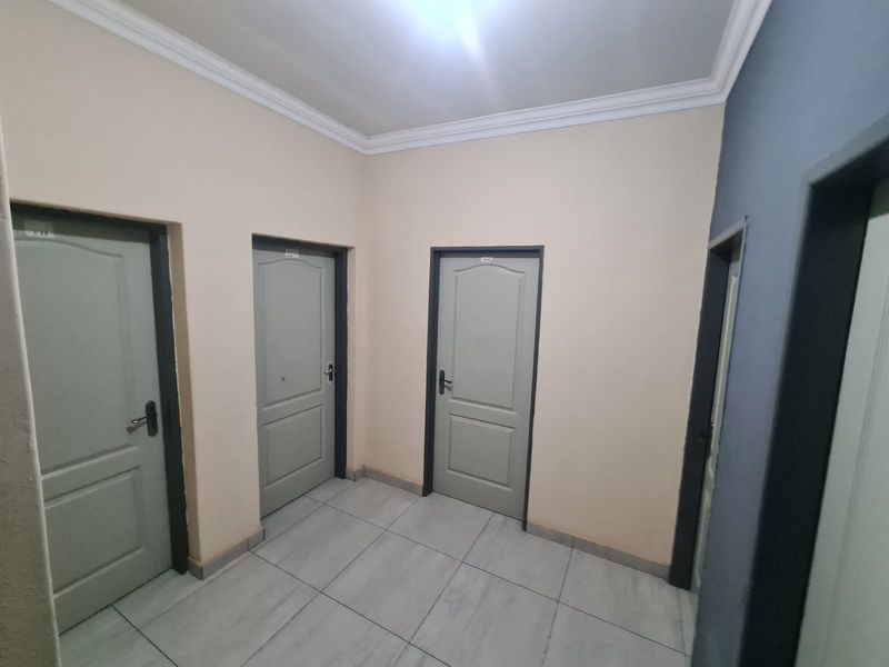 A clean, empty hallway featuring tiled flooring, neutral wall paint, and multiple internal doors with contrasting frames.