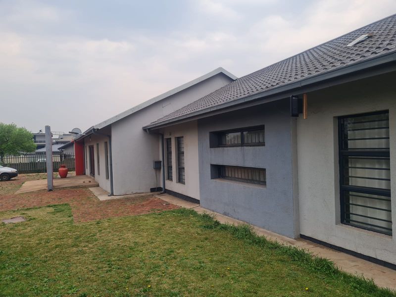 Rear view of the house featuring a tiled roof, brick paved patio area, and security bars on the windows.