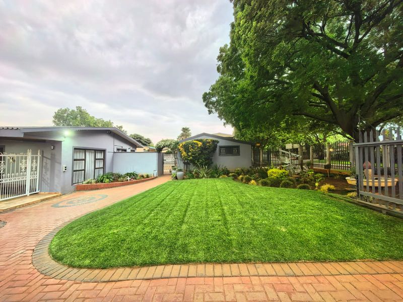 A well-maintained front exterior featuring a paved driveway, manicured lawn, and mature trees, providing an inviting and tidy entrance to the property.