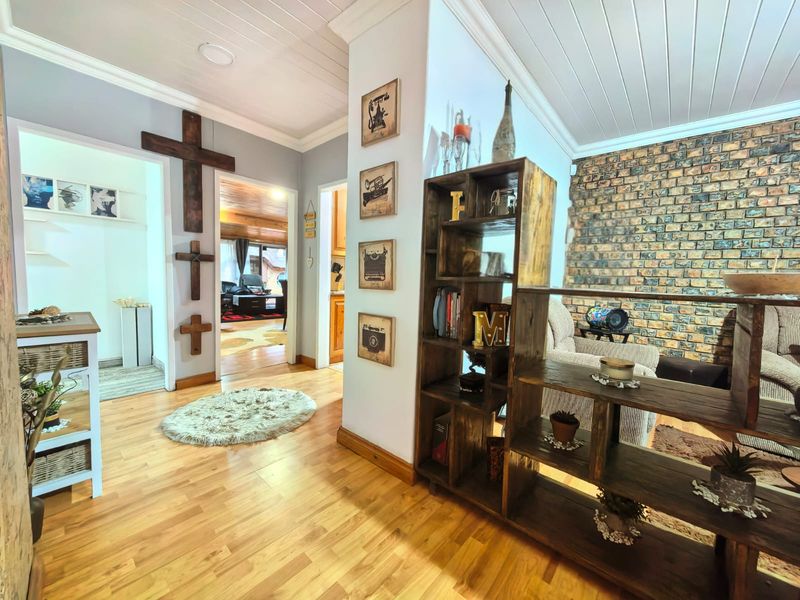 A well-maintained hallway featuring timber flooring, a rustic exposed brick feature wall, and a classic tongue and groove ceiling with recessed lighting.