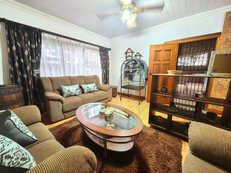 A comfortable living room featuring laminate flooring, a ceiling fan, and a solid timber door with an integrated security gate.