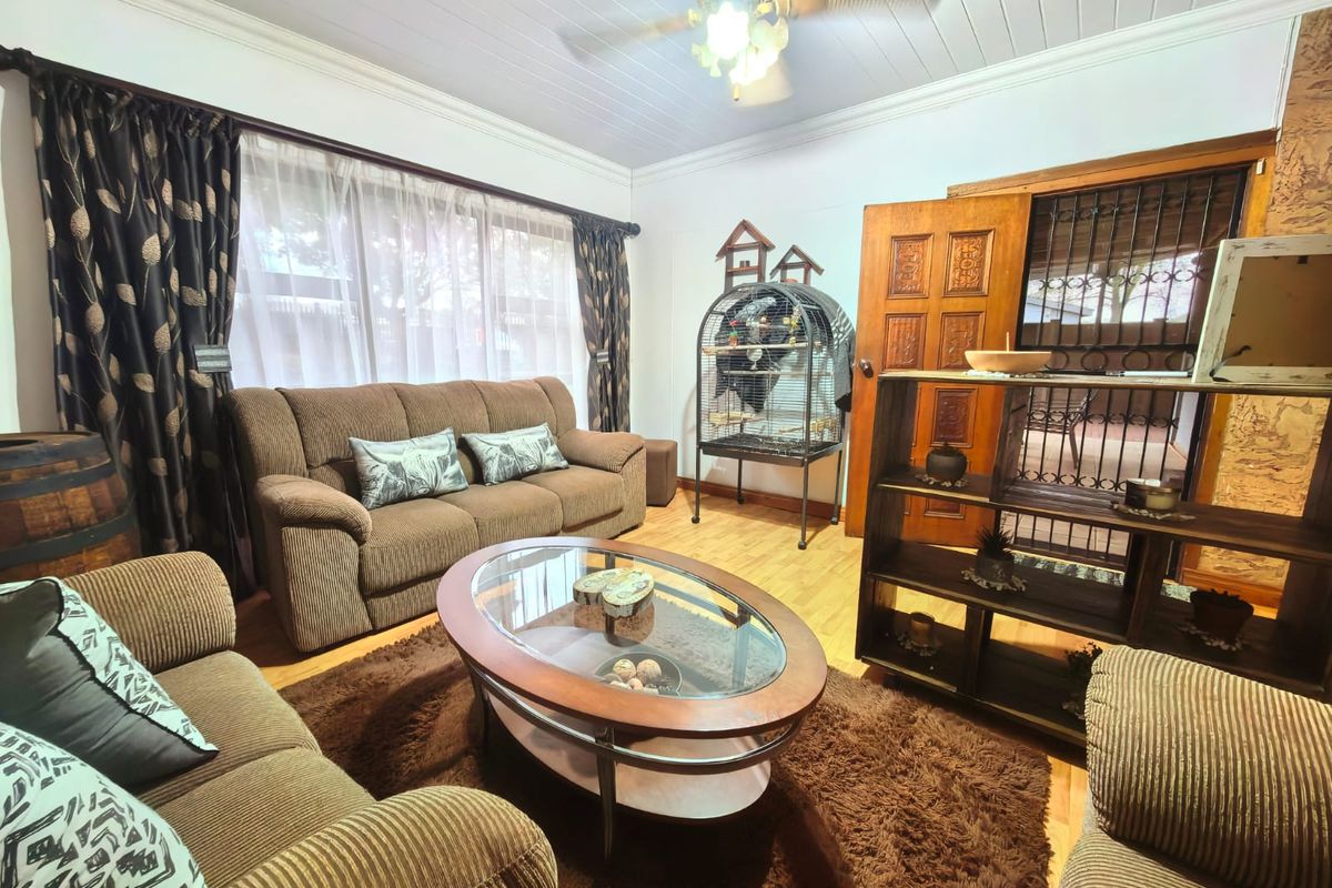 A comfortable living room featuring laminate flooring, a ceiling fan, and a solid timber door with an integrated security gate.
