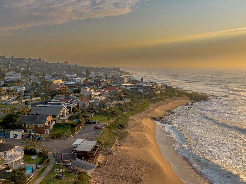 An elevated aerial view capturing the coastal landscape, residential properties, and the expansive shoreline at sunset.
