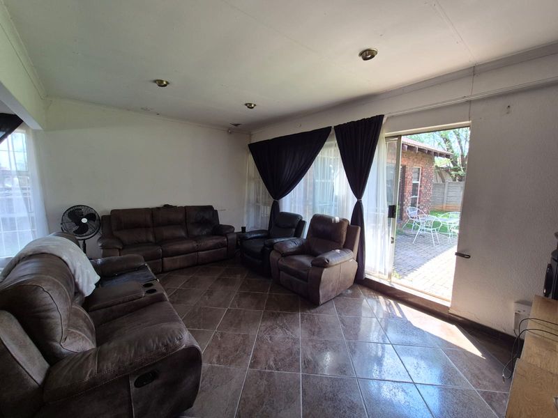 Spacious living room featuring tiled flooring and a sliding glass door providing direct access to the rear patio area.