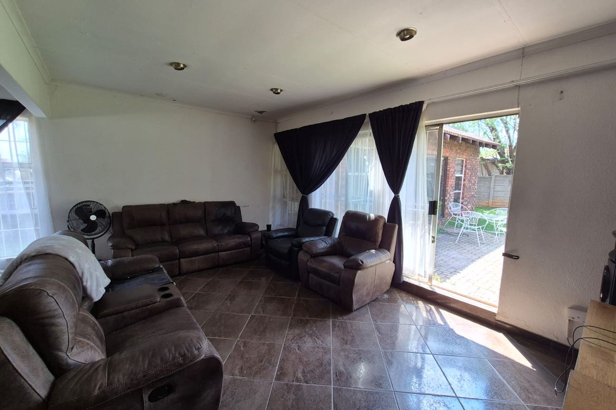 Spacious living room featuring tiled flooring and a sliding glass door providing direct access to the rear patio area.
