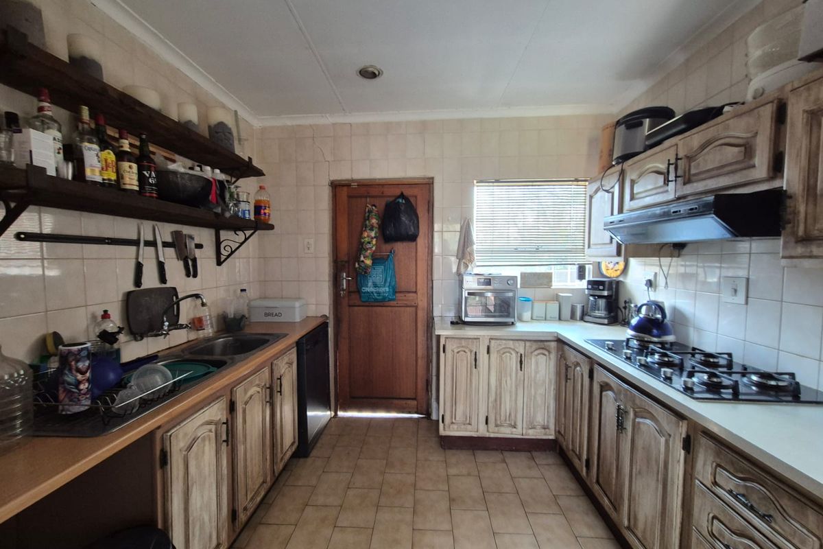 A functional kitchen featuring built-in cabinetry, a gas hob with extractor fan, double sink, and tiled finishes throughout.