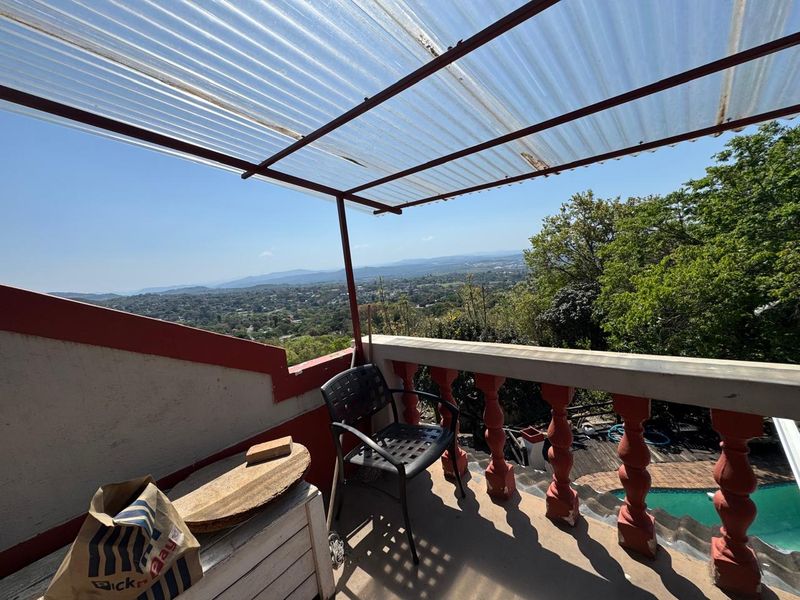 An elevated balcony featuring a corrugated plastic roof, concrete balustrade, and expansive panoramic views of the surrounding landscape.