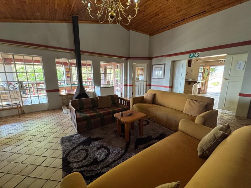 Spacious living room featuring a vaulted timber ceiling, tiled flooring, and a central freestanding fireplace with direct access to the patio.