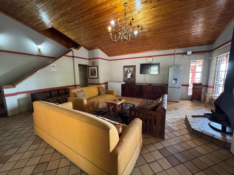 Spacious living room featuring a high timber-clad vaulted ceiling, ceramic tile flooring, and a freestanding fireplace, offering a rustic and open layout.
