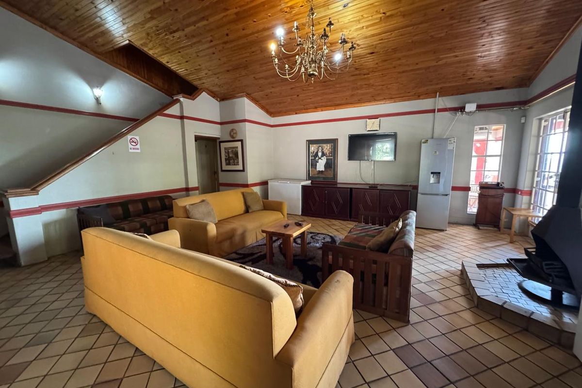 Spacious living room featuring a high timber-clad vaulted ceiling, ceramic tile flooring, and a freestanding fireplace, offering a rustic and open layout.