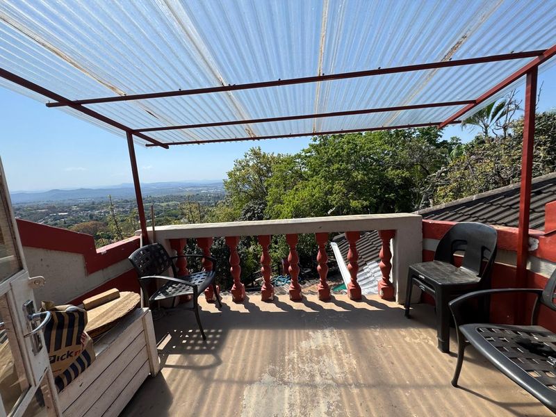 An elevated balcony featuring a corrugated roof, concrete balustrade, and expansive scenic views, offering potential for a refreshed outdoor entertainment space.