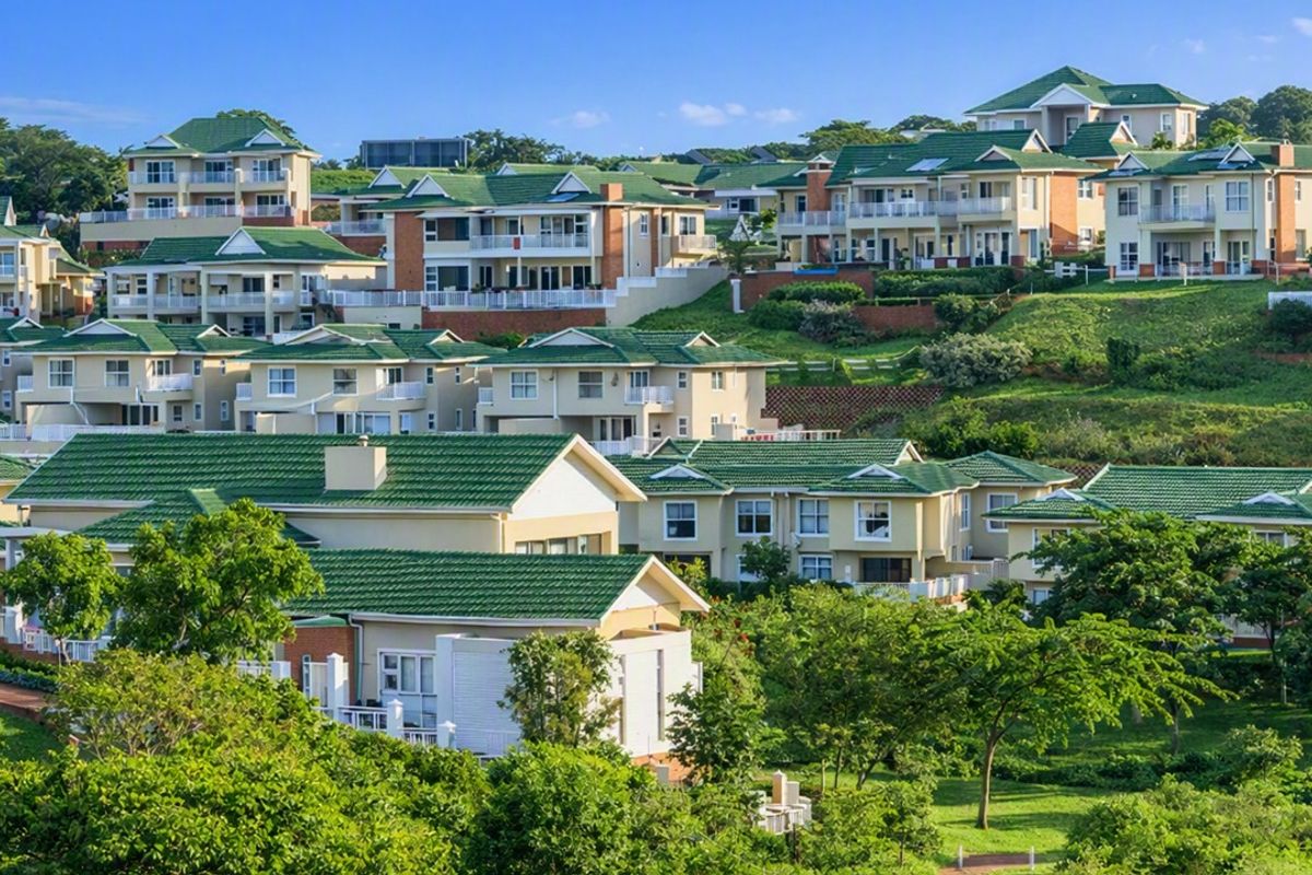 An elevated aerial view of a residential estate featuring multiple homes with green tiled roofs set within a landscaped, terraced environment.