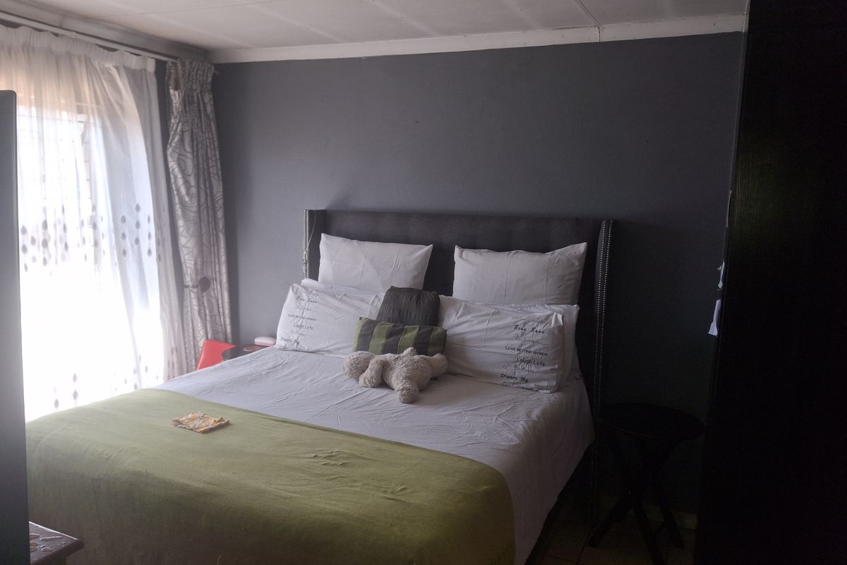 A bedroom featuring tiled flooring and neutral wall finishes, providing a functional space with natural light access.