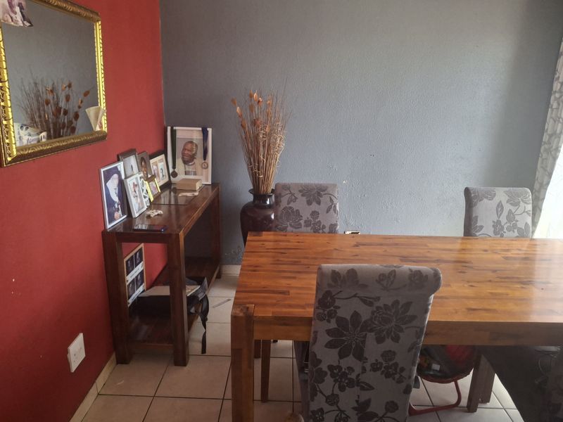 A dining room featuring ceramic floor tiles and contrasting red and grey painted walls, providing a functional space for family meals.