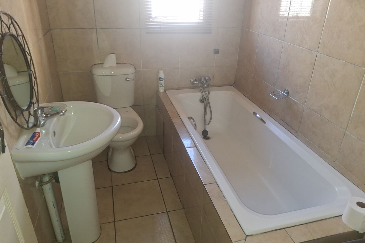 A functional bathroom featuring a pedestal basin, toilet, and a built-in bathtub with tiled wall and floor finishes.